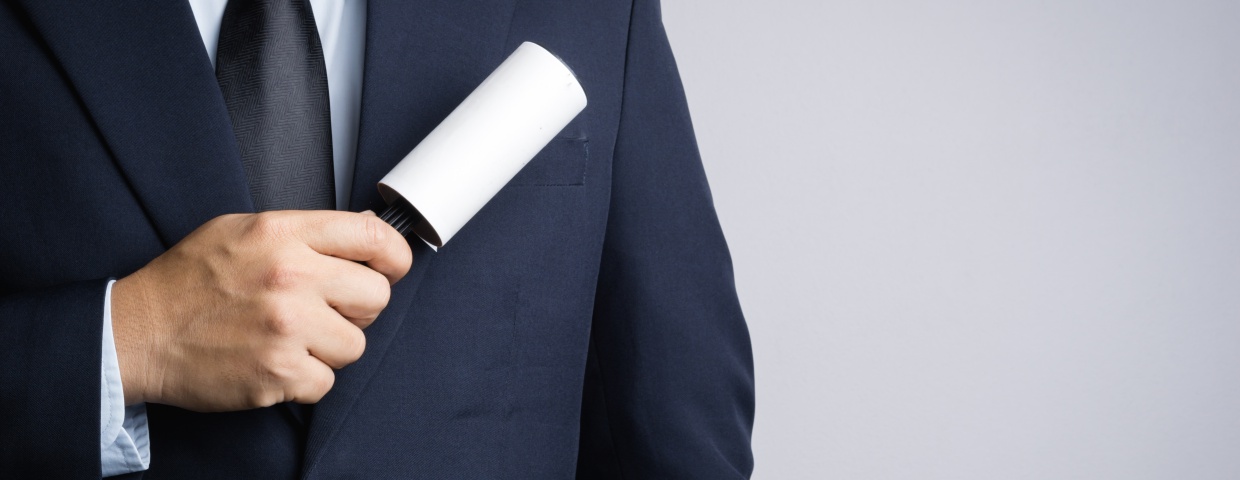closeup of man using lint roller on suit coat, cleaning and care concept
