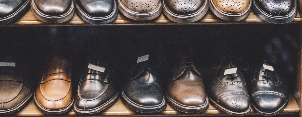 closeup of mens dress shoes on shelf, varying styles and colors