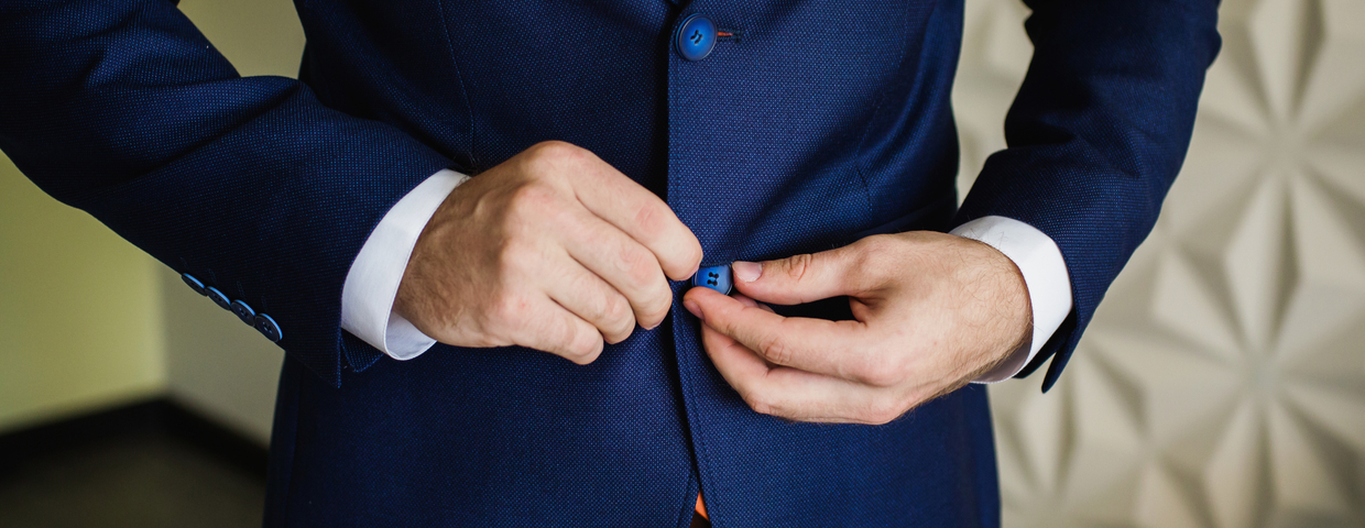 closeup of man in navy suit buttoning button