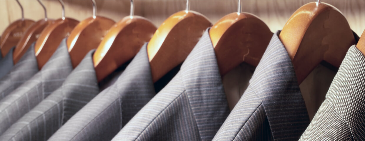 row of mens suit jackets hanging in closet