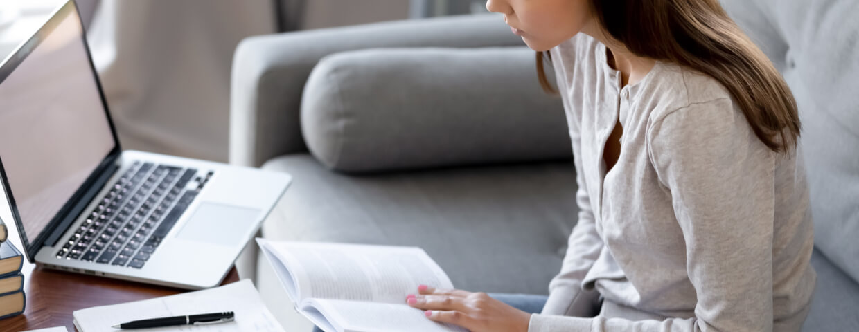 teen doing research on the computer and with books